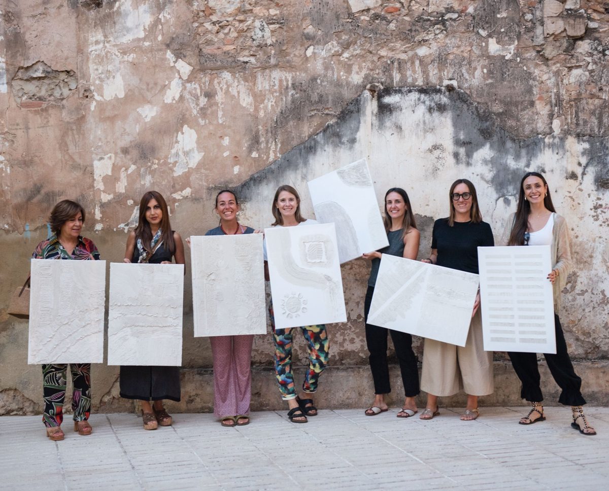 Grupo del taller con sus cuadros terminados, delante de un muro antiguo