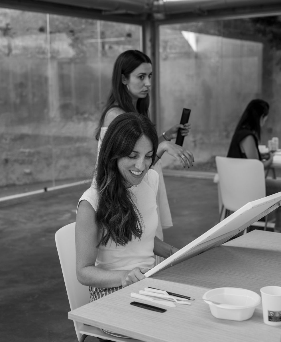 Irene sonriendo mientras prepara un lienzo en el taller, en blanco y negro