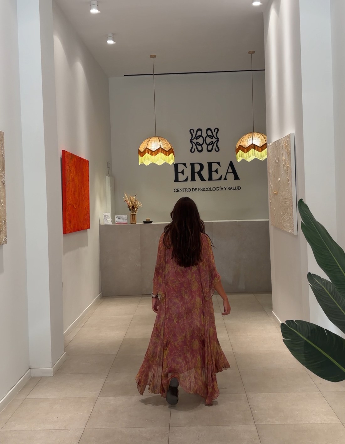 Irene caminando hacia la recepción de EREA, entre cuadros de la exposición
