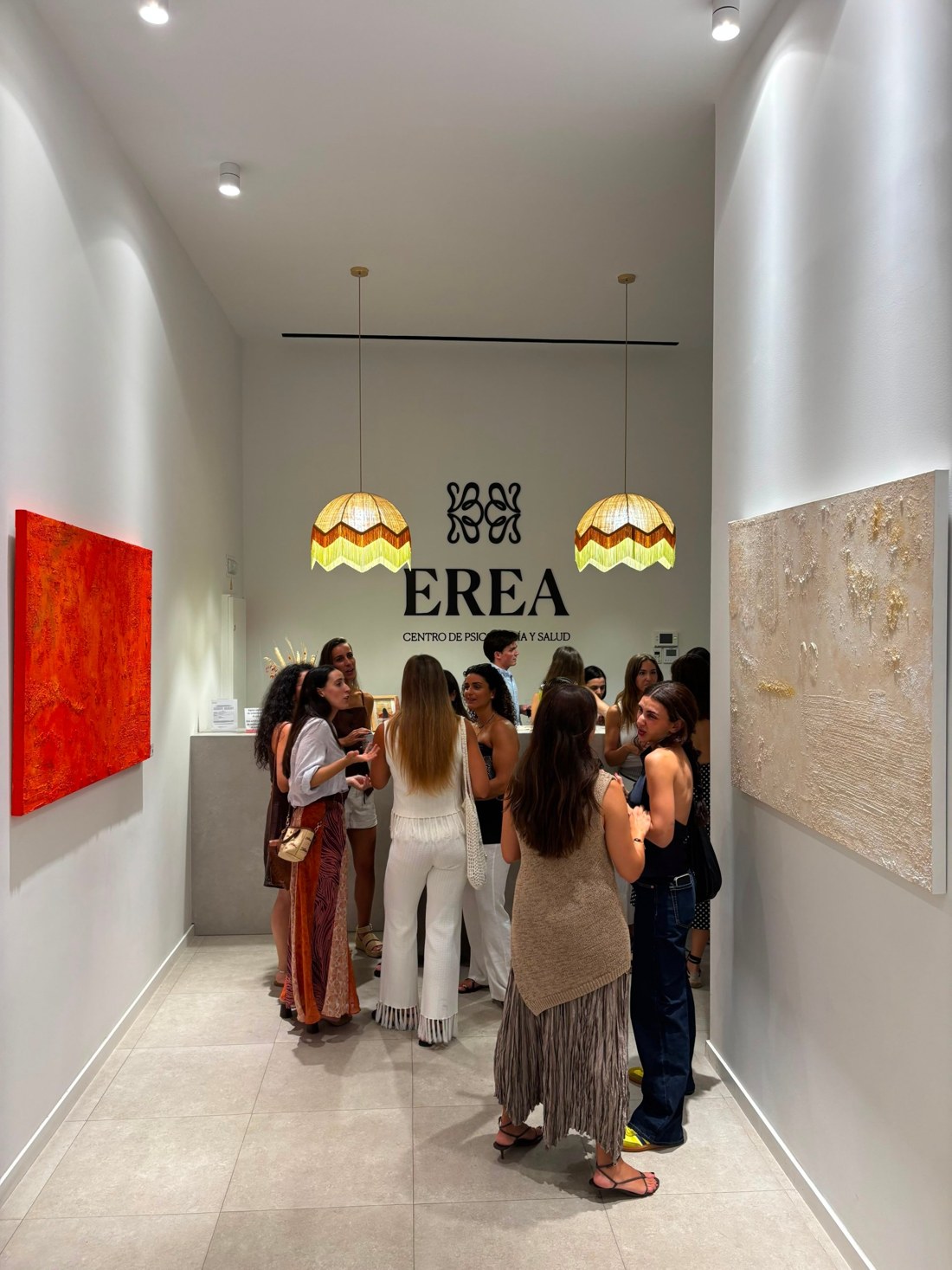 Inauguración de Entre Capas en EREA, con personas conversando entre los cuadros