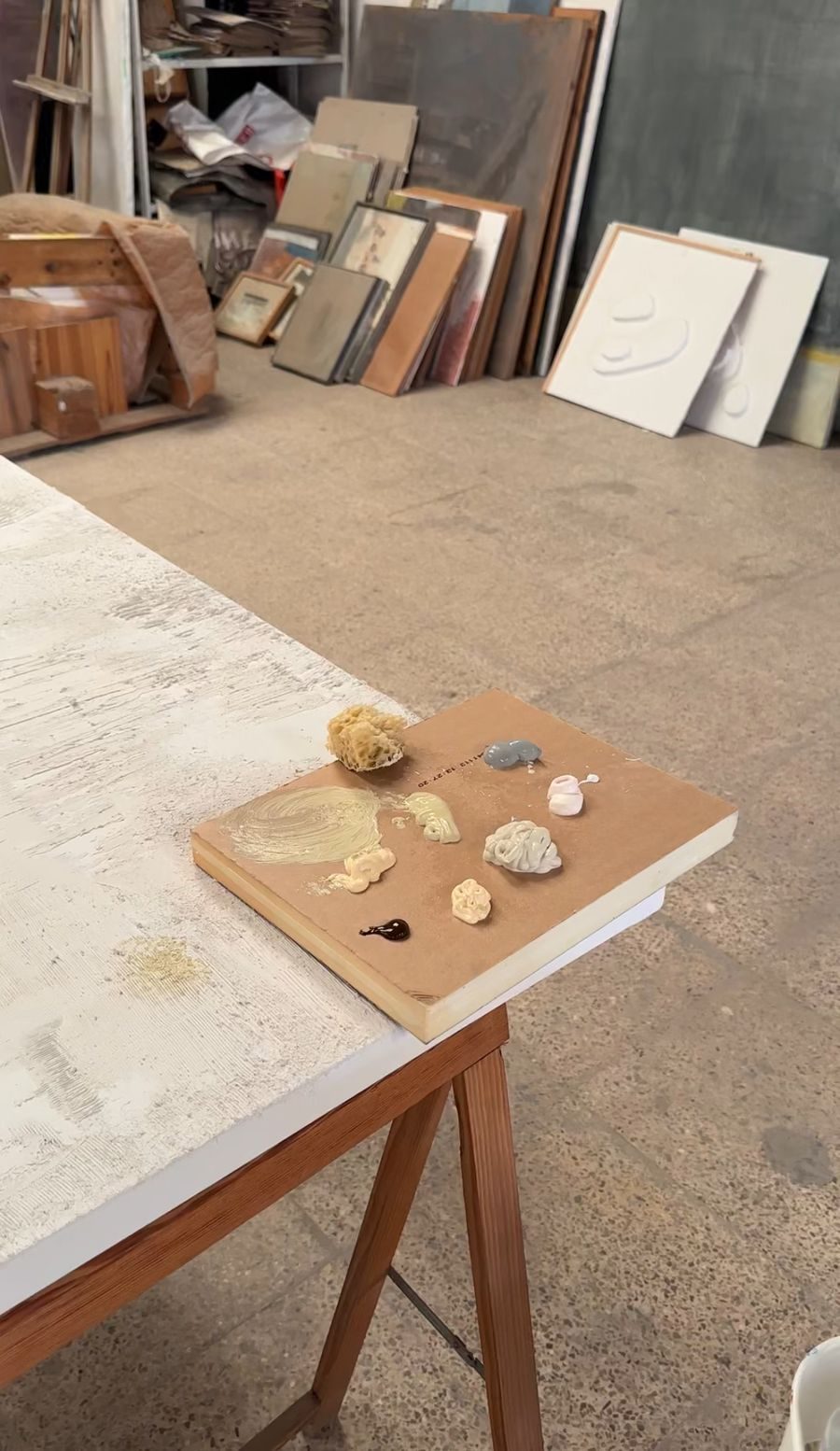 Paleta de colores y una esponja sobre un lienzo con textura, en el taller