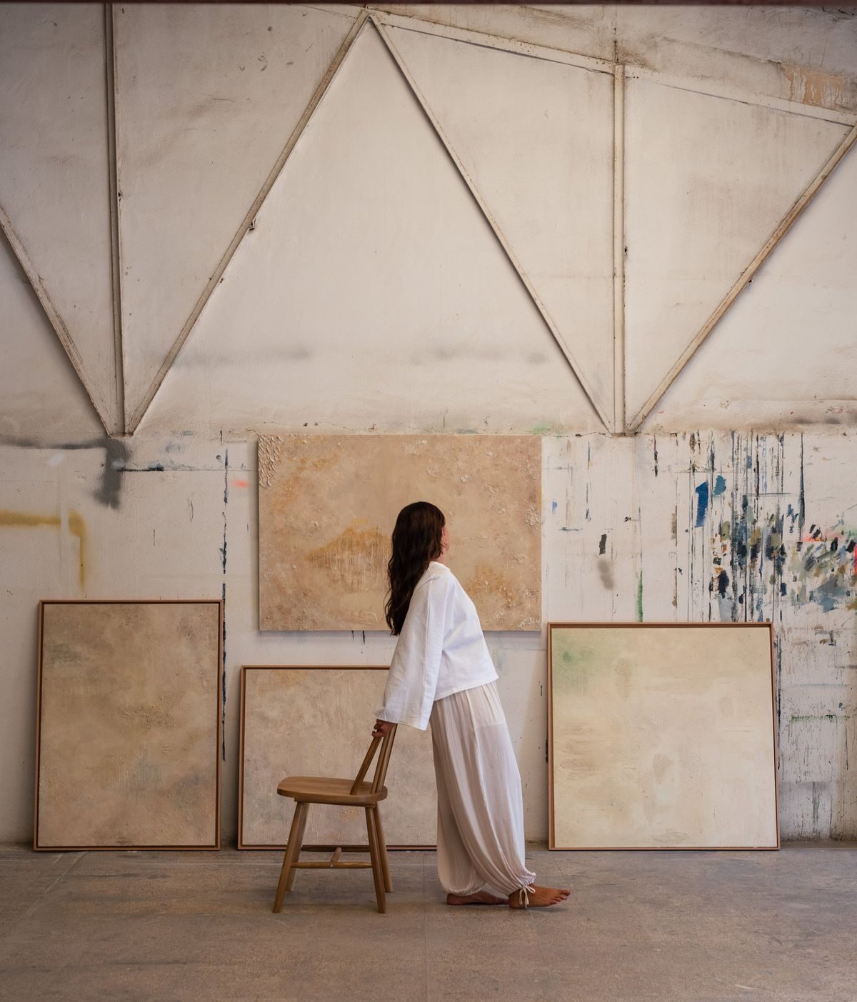 Irene apoyada en una silla de madera, en su estudio