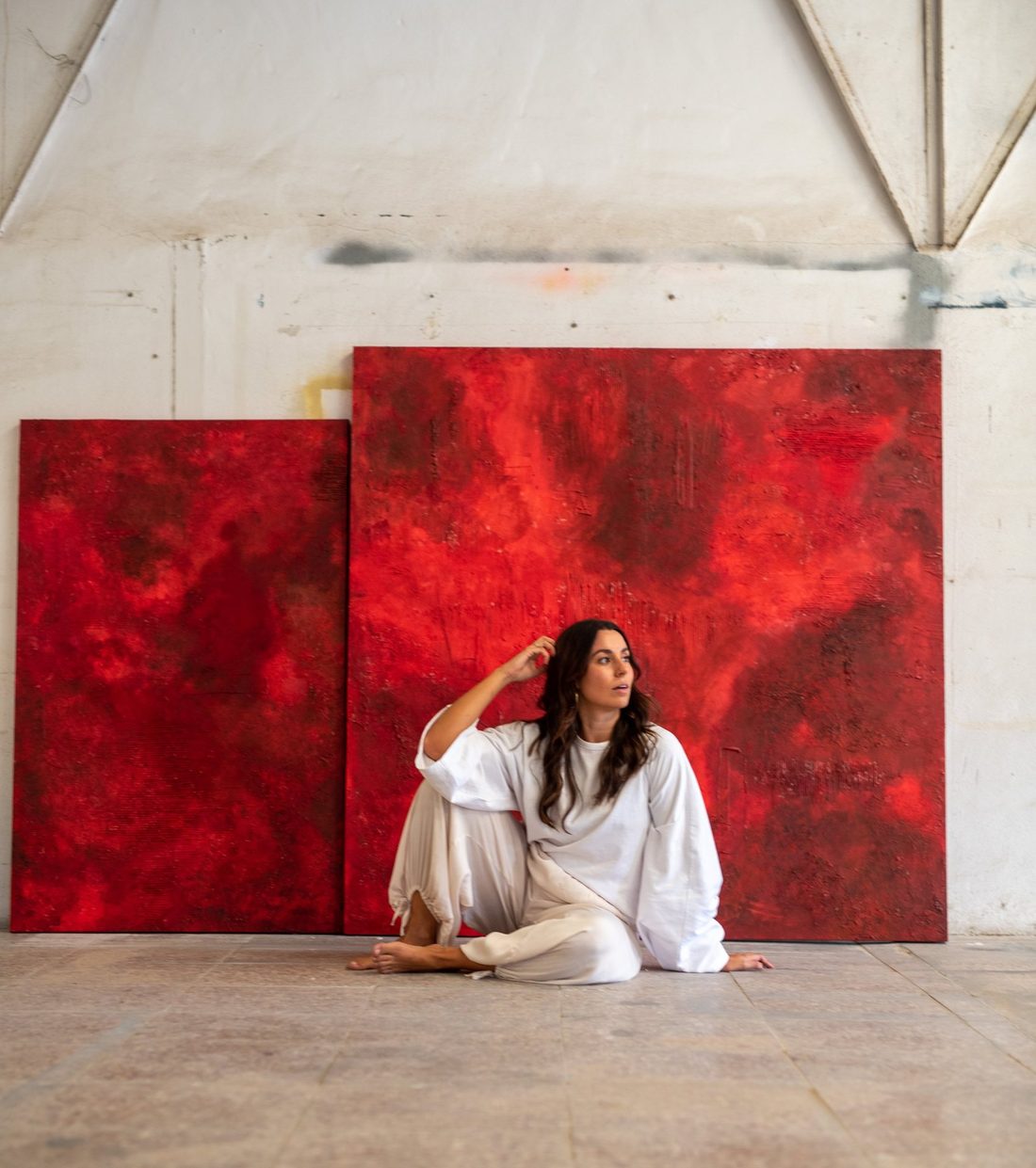 Irene sentada en el suelo del estudio delante de dos grandes cuadros rojos con textura